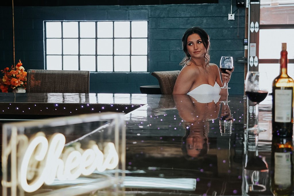 A bride with a glass of red wine at the light-up bar.