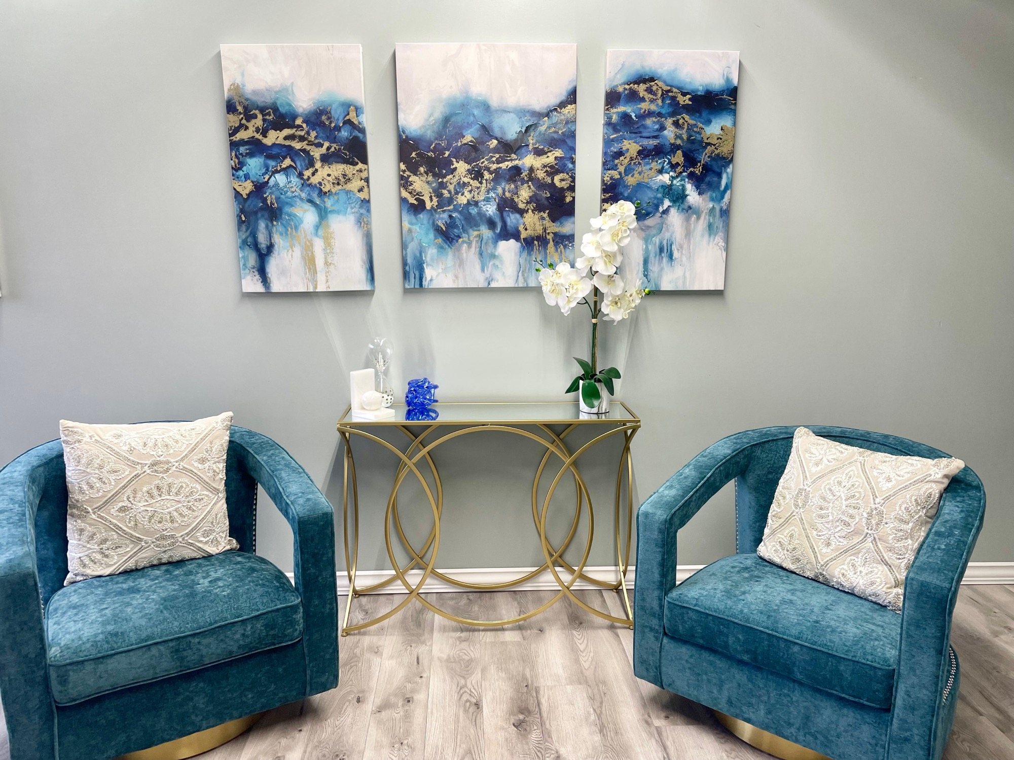 The Bridal Suite lounge, with two teal velvet armchairs, a gold console table and abstract art.