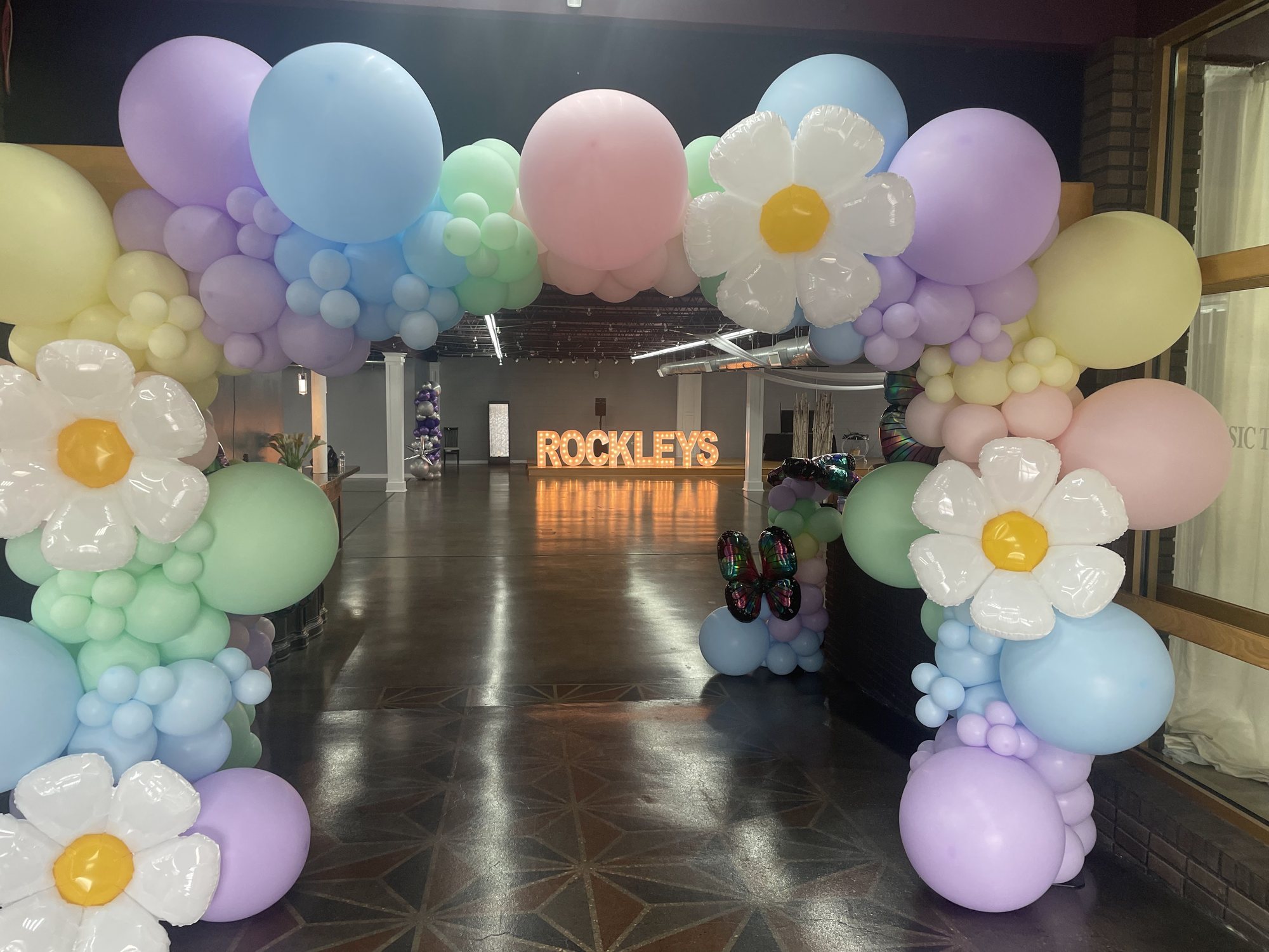 A pastel balloon arch with daisies framing the Rockleys entrance.