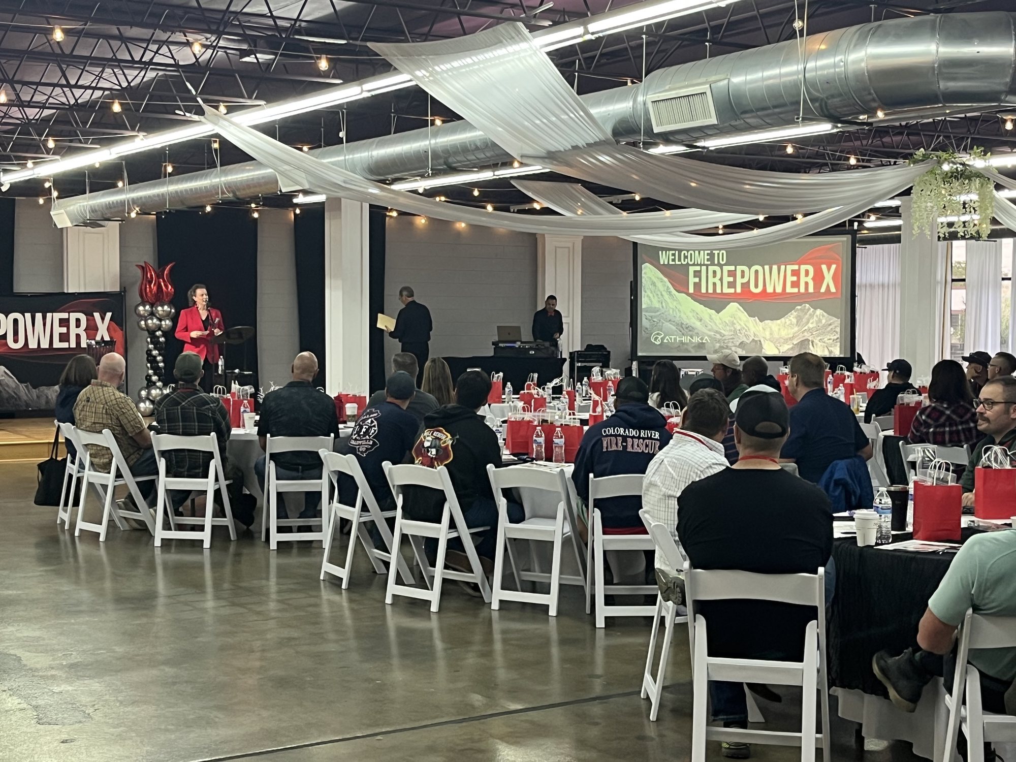 A company presentation in the ballroom, guests at round tables facing the screen.